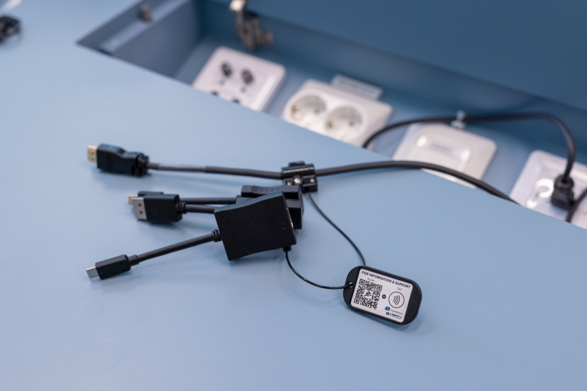 Organiserade kablar, samt en bricka med en QR-kod i förhandlingssal