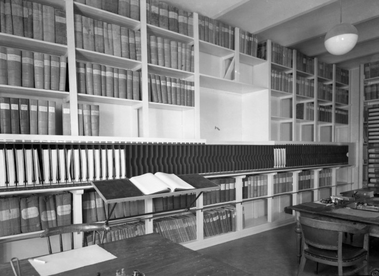 Interiör arkivet. Pärmar och böcker i bokhyllor. Svartvitt.