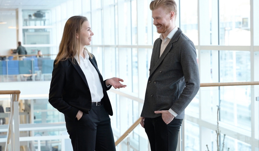 En kvinnlig och en manlig notarie står och pratar med varandra.