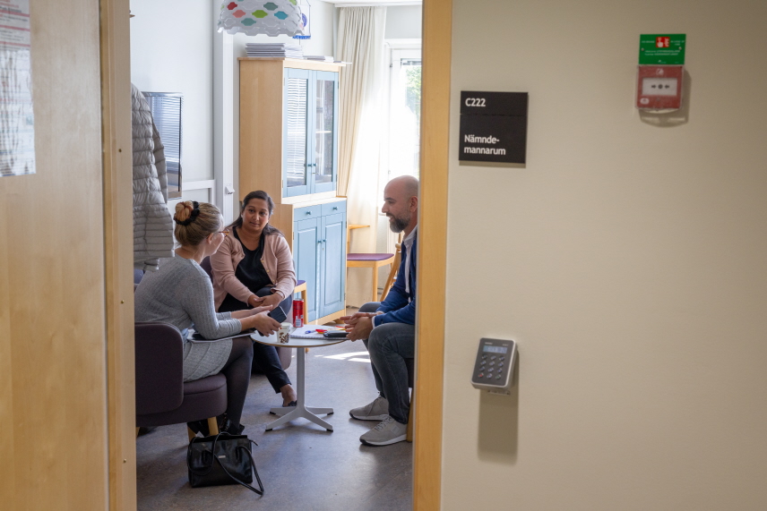 Tre nämndemän sitter vid ett bord och pratar.