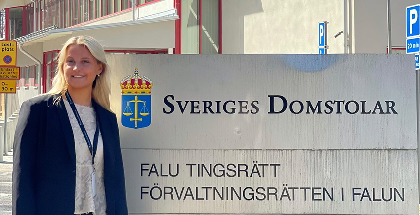 Kvinnlig nämndeman står framför domstolsskylt.