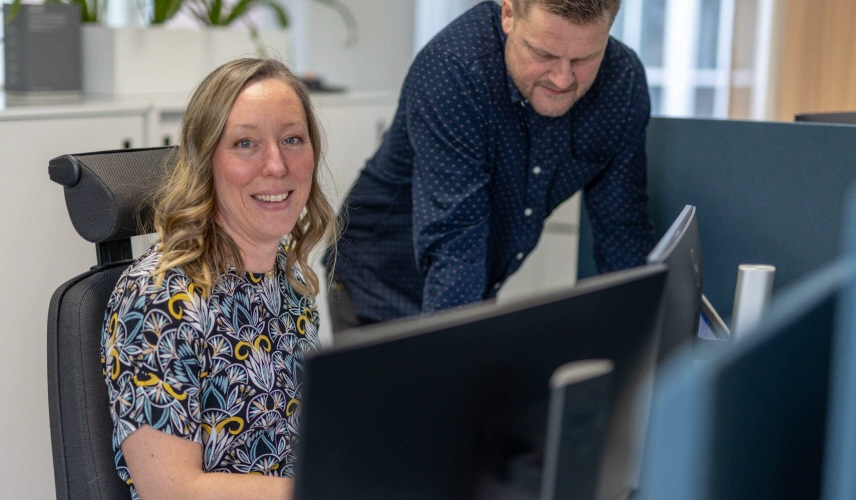 En kvinna och en man diskuterar framför en dator.