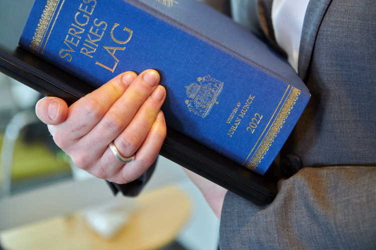 Domstolsmedarbetare bär lagbok.