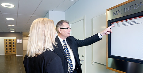 Man som pekar på informationstavla. Foto.